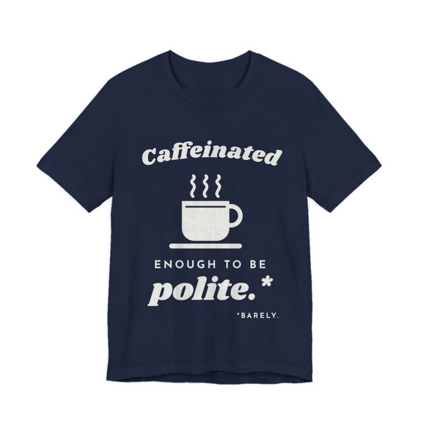 Navy t-shirt printed in off-white ink with “Caffeinated” over a steaming coffee cup, then “Enough to Be polite.*” with a tiny footnote: “*Barely.”
