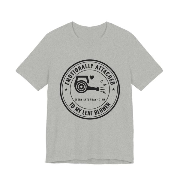 Athletic Heather t-shirt printed in dark ink with a round badge reading “Emotionally Attached to My Leaf Blower” around a leaf blower with a little heart, plus “Every Saturday · 7 AM”