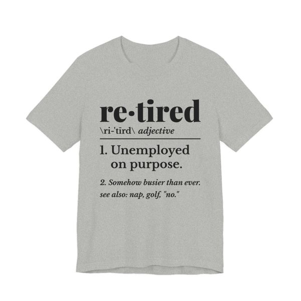 Athletic Heather t-shirt printed in dark ink with a dictionary entry: “re·tired, adjective. 1. Unemployed on purpose. 2. Somehow busier than ever. See also: nap, golf, “no.””