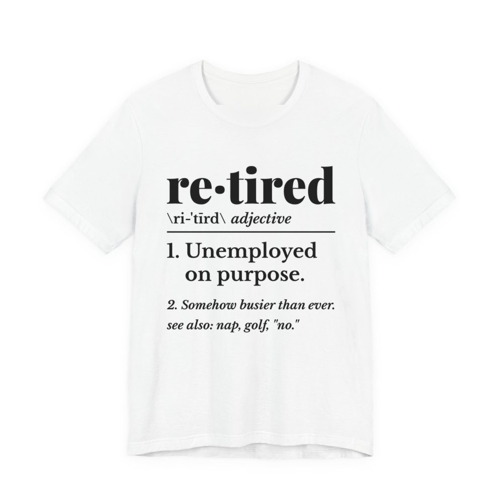 White t-shirt printed in dark ink with a dictionary entry: “re·tired, adjective. 1. Unemployed on purpose. 2. Somehow busier than ever. See also: nap, golf, “no.””